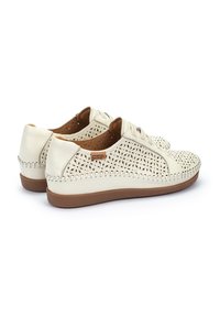 Zapatos de cuero blanco con cordones que presentan patrones florales perforados, acentos de cuero marrón y una suela de goma texturizada.
