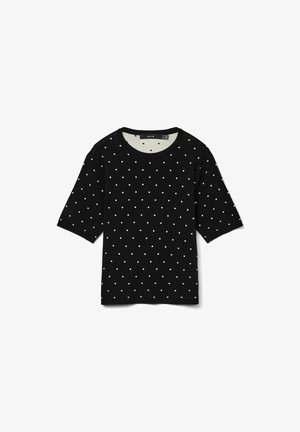 Camiseta de manga corta negra con lunares blancos, cuello redondo y textura suave. Presenta un corte informal y un diseño minimalista.