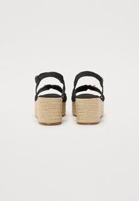 Schwarze Keilsandaletten mit geflochtenem Jute-Absatz, verstellbaren Knöchelriemen und strukturiertem schwarzen Stoff. Solides Plattformdesign.