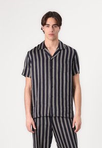 Camicia a maniche corte blu navy con strisce verticali beige, chiusura frontale con bottoni e taschino sul petto. Realizzata in tessuto leggero con una vestibilità comoda.