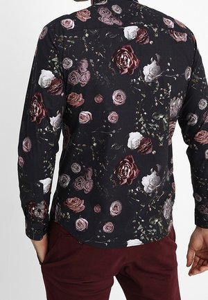 Langarmshirt met een zwarte stofbasis, voorzien van een bloemmotief in bordeauxrood, roze en witte rozen, met subtiele groene accenten.