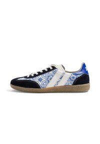 Baskets basses avec motif floral bleu et blanc, bout et talon en daim noir, rayures blanches, languette de talon bleue et semelle en caoutchouc naturel.