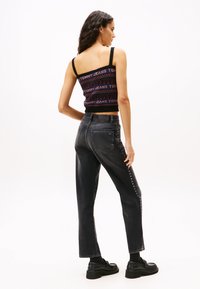 Jeans negros de corte recto, con tachuelas plateadas a lo largo del lado. Combinados con un top de punto multicolor y cropped con diseño de logo.