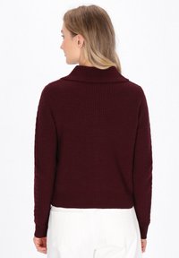 Weinroter Strickpullover mit weitem Kragen, strukturiertem Muster und gerippten Bündchen. Kurze Passform und einfarbig ohne sichtbare Hardware.