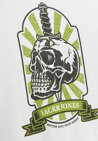 Grafiska T-kreklu ar skeleta motīvu ar zobenu virsū, zaļām un baltām staru fona, un "JACK & JONES" baneri apakšā.
