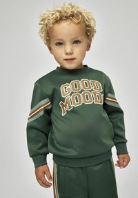 Grön sweatshirt med texten "GOOD MOOD", långa ärmar och randiga detaljer. Mjuk textur, tillsammans med matchande byxor med fickor.