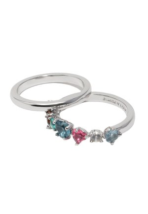 Dwa srebrne pierścionki, jeden gładki, a drugi z różnokolorowymi kamieniami szlachetnymi, w tym niebieskimi, różowymi i przejrzystymi kamieniami w różnych kształtach.