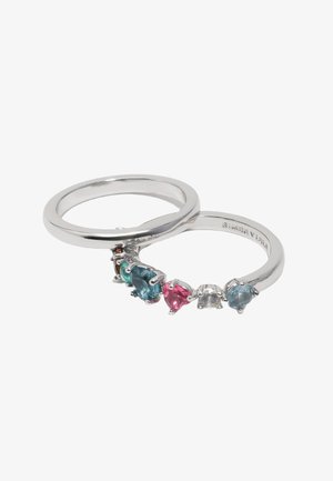 Dva strieborné prstene, jeden jednoduchý a druhý osadený rôznofarebnými drahokamami vrátane modrých, ružových a čírych kameňov rôznych tvarov.