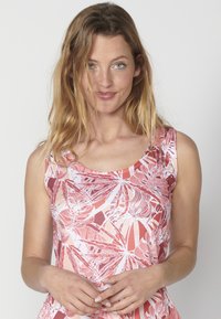 Débardeur sans manches à motif floral dans les tons de rose et blanc, avec un motif de feuilles, un col rond et une coupe décontractée. Texture de tissu douce.
