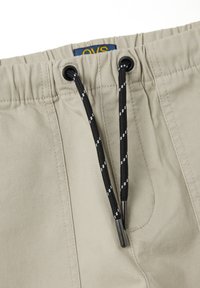 Beige shorts met elastische tailleband en een zwarte trekkoord met witte accenten. OVS-logo gestikt aan de binnenzijde van de tailleband, soepele stofstructuur.