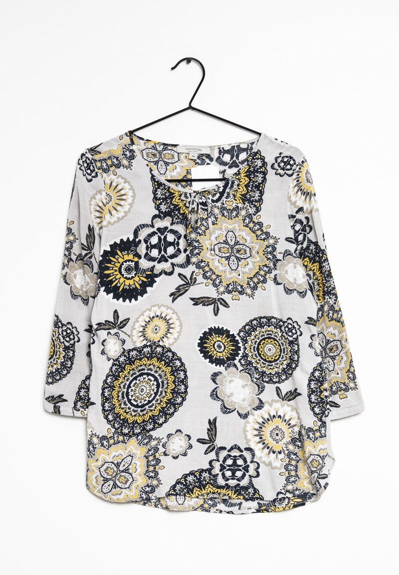 Blouse à manches longues avec un fond gris, présentant un motif floral en noir, jaune et blanc. Tissu texturé ; coupe ample ; encolure ronde.