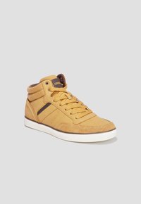 Zapatilla alta en ante amarillo con acentos marrones, puntera redonda, suela de goma y cordones planos. Presenta un cuello acolchado y un logo en el lateral.