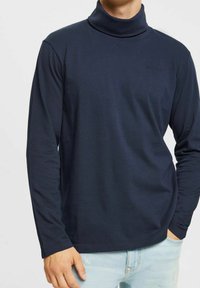 Mörkblå polotröja med långa ärmar, tillverkad av mjukt tyg. Har en slim fit och en minimalistisk design med en diskret logotyp på bröstet.