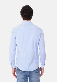Camicia da uomo con bottoni, realizzata in tessuto leggero, con strisce verticali blu e bianche, caratterizzata da un colletto classico e maniche lunghe.