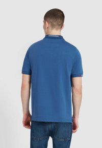 Blauwe polo met korte mouwen en een effen ontwerp. Heeft een gestreepte kraag en accenten op de mouwmanchetten. Gemaakt van een katoenen mix.