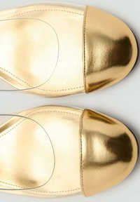 Talons hauts en cuir doré avec un bout arrondi, texture lisse et finition brillante. Présente un capuchon doré contrastant au niveau du bout.
