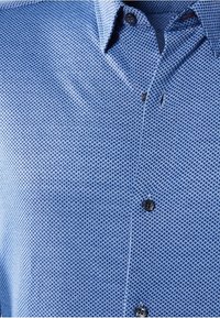 Camicia azzurro chiaro con un motivo testurizzato, design a bottone e bottoni neri. Presenta un colletto standard e dettagli sottili.