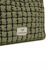 Groene, gevoerde tas met een unieke textuurontwerp en ronde vormen. Bevat een merketiket met "UNIO" en "X LES VISIONNAIRES."