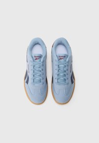 Jasnoniebieskie zamszowe sneakersy z gumową podeszwą, z białym wyściełanym językiem i sznurowanym przodem, zaakcentowane ciemnoniebieskimi paskami i logo.