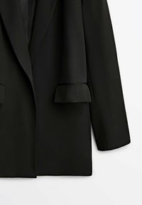 Black blazer with a smooth texture, featuring a notched lapel and rolled cuffs. Classic tailored design, without visible fastenings or patterns.