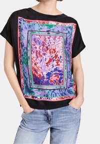 Top de manga corta negro con un estampado abstracto multicolor con cuadrados, en tonos de púrpura, rosa, verde y rojo en la parte delantera.