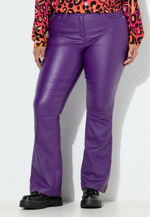 Pantalons en simili cuir violet avec une finition lisse, dotés d'une taille ajustée, de jambes droites et de poches avant. Associés à des bottes à plateforme noires épaisses.