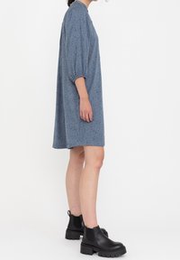 Abito corto blu con vestibilità comoda, maniche a palloncino e motivo a pois neri, abbinato a chunky ankle boots neri.