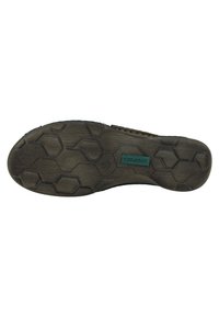 Suola di scarpa nera in gomma con un motivo di battistrada esagonale e un logo verde del brand. Superficie testurizzata con lievi segni di usura.
