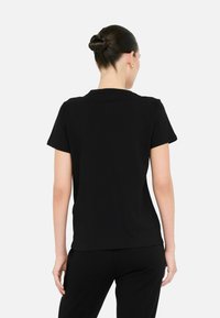 Sort kortærmet t-shirt med rund halsudskæring og lige kant, lavet af et blødt stof. Ingen synlige mønstre eller accenter.