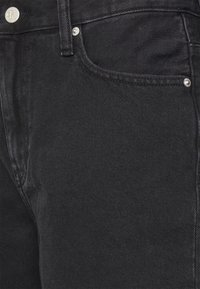 Svarta denimjeans med en klassisk femficksdesign, silverfärgade metallaccenter samt en strukturerad, något urblekt yta.