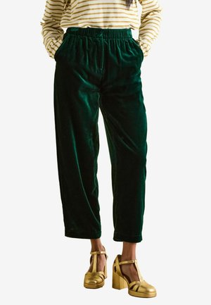 Dark green velvet pants with an elastic waistband, featuring a loose fit and side pockets, paired with gold platform shoes.