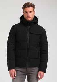 Sort pufferjakke med hætte, lynlås lukning, frontlomme og sidelommer. Har en quiltet design og glat tekstur.