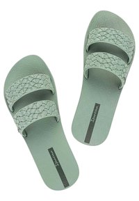 I sandali di gomma verdi presentano due cinghie intrecciate e una suola texturizzata. La soletta include un logo del marchio in colore scuro.