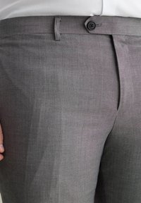 Grijze broek met een gladde textuur, voorzak en een enkele zwarte knop bij de tailleband. Minimalistisch ontwerp met strakke lijnen.