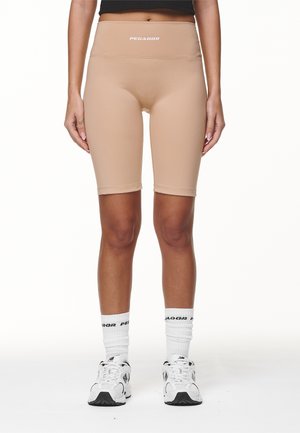 Beige jalgrattashortsid kõrge vööosaga, valmistatud siledast ja venivast materjalist. Vööosas ja põlvepikkuses on valge logo.