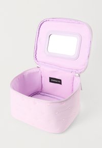 Lila párnázott sminktasak, apró szívmintákkal, nyitott zippzárral és beépített téglalap alakú tükörrel a belső fedélen.