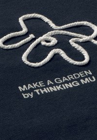 Tessuto blu navy con design a loop ricamato bianco e testo: "FAI UN GIARDINO pensato da THINKING MU" in un font moderno, enfatizzando texture e contrasto.