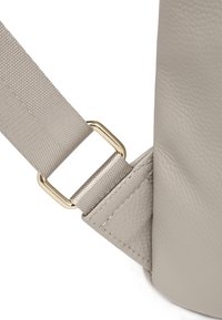 Angolo di una borsa a tracolla grigia in pelle con finitura testurizzata, una fibbia in metallo dorato e una tracolla in tessuto coordinato con un motivo sottile.