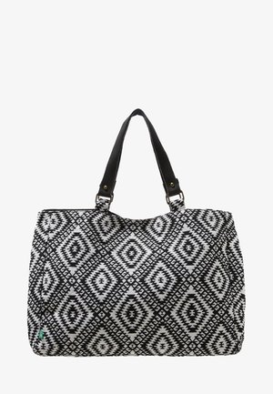 Torba typu tote w biało-czarny wzór z kształtami diamentów i dwoma czarnymi uchwytami przymocowanymi metalowymi pierścieniami.