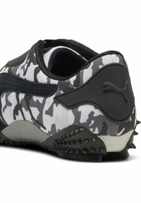 Zwart-wit sneaker met camouflagepatroon, voorzien van een textuur rubberen buitenzool en opvallende zwarte accenten, met een logo-detail.