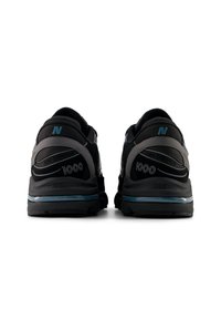 Μαύρα αθλητικά παπούτσια με πλέγμα και συνθετικό υλικό, με επενδεδυμένη φτέρνα, μπλε λεπτομέρειες και αντανακλαστικά στοιχεία. Αριθμός μοντέλου 1000.