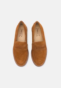 Donkerbruine lederen instappers met een iets verhoogde voorkant, gestikte accenten en een ronde neus. Gladde binnenvoering en gevoerde binnenzool.