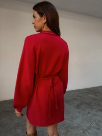 Czerwona sukienka z paskiem, długimi rękawami i luźnym krojem. Żebrowany dekolt i wiązanie w talii. Gładka faktura, noszona z wysokimi kozakami do kolan.