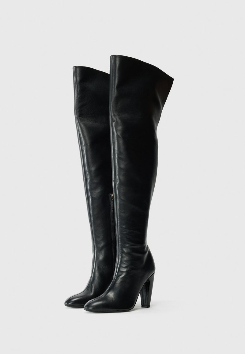 Schwarze Leder-Stiefel über dem Knie mit einem eleganten Design, spitzer Zehenform und hohem Absatz. Verfügt über einen seitlichen Reißverschluss und eine glatte Textur.