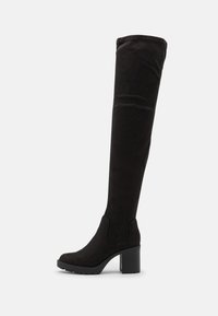 Botas negras de ante por encima de la rodilla con un tacón sólido, punta redonda y paneles laterales elásticos para facilitar su uso. Superficie texturizada.