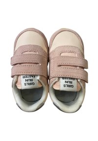 Un paio di sneaker per bambini di colore rosa e beige con doppie cinghie in velcro e etichette bianche sulla linguetta che recitano "LE RAGAZZE CORRONO PIÙ VELOCE".