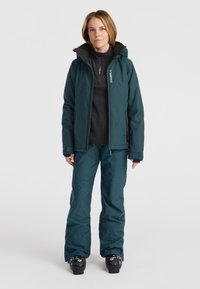 Teal ski jacket and pants feature a fitted design with a waterproof texture. Includes a hood, zippered pockets, and embroidered logo details.