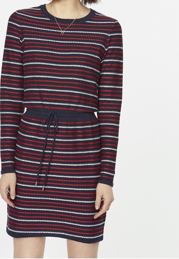 Pruhované šaty s dlouhými rukávy, vyrobené z pleteniny. Má vodorovné červené, námořnické a bílé pruhy, s elastickým pasem a žebrovanými manžetami.