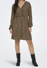 Langärmliges Wickelkleid in einem tan- und schwarz-gefleckten Leopardenmuster, mit V-Ausschnitt und definierter Taille, kombiniert mit schwarzen Stiefeletten.