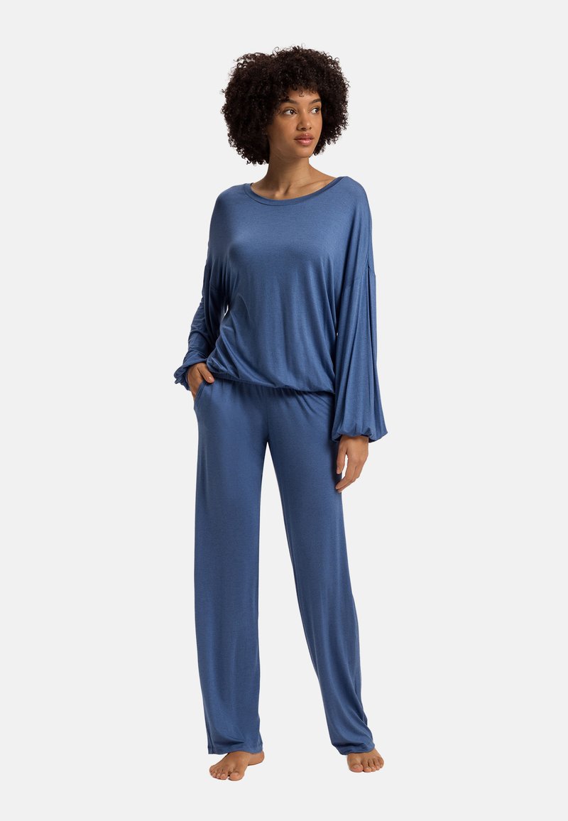 Modrý loungewear set složený z volného dlouhého rukávu a širokých kalhot, vyrobený z měkkého, hladkého materiálu s jemným leskem.